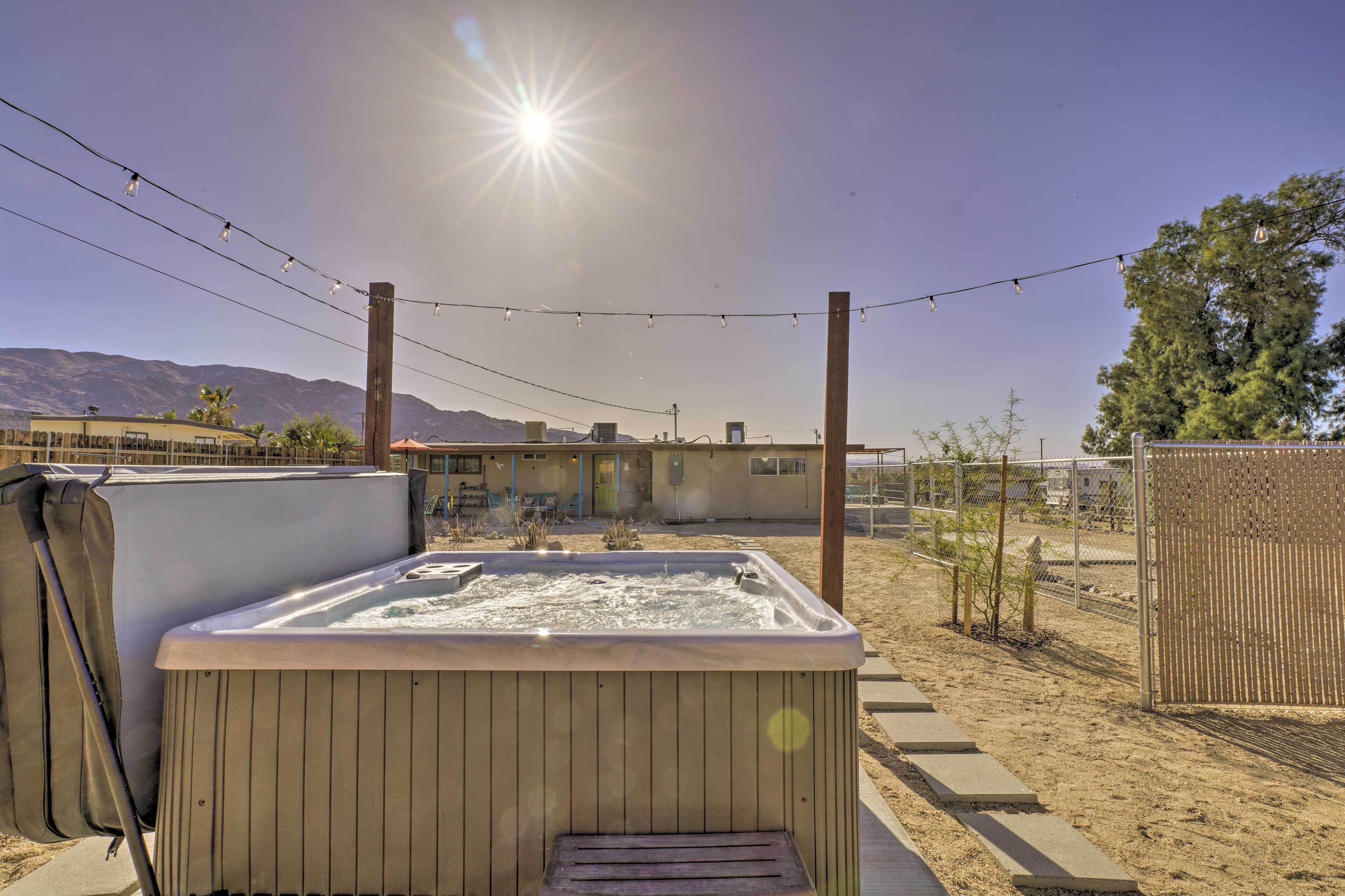 A hot tub in a backyard with a clear sky and mountains in the background.