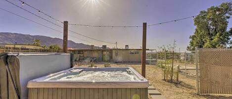 A hot tub in a backyard with a clear sky and mountains in the background.