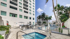 A rooftop pool area with a swimming pool, palm trees, and a high-rise building in the background. - Modern Ft Lauderdale Condo ~ 7 Mi to Airport! (Fort Lauderdale)