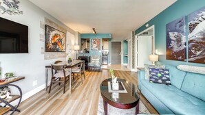 A spacious living room with a blue sofa, wooden dining table, and a kitchen in the background. - Modern Ft Lauderdale Condo ~ 7 Mi to Airport! (Fort Lauderdale)