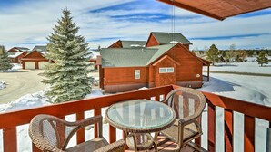 A wooden deck with wicker chairs and a glass table overlooking a snowy landscape with houses. - Pagosa Springs Vacation Rental w/ Boat Dock! (Pagosa Springs)