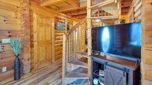 Un intérieur en bois avec un escalier, un téléviseur à écran plat et un vase avec des plantes.