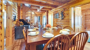 L’intérieur d’un chalet en bois présente une table à manger pour quatre personnes, entourée de chaises en bois.