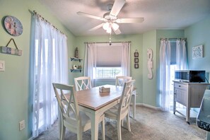 A dining area with a table, chairs, a ceiling fan, and a kitchen area with a microwave.
