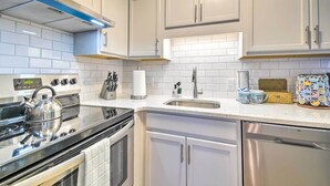Une cuisine moderne avec des meubles blancs, un lave-vaisselle en acier inoxydable et une cuisinière noire.