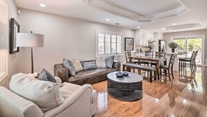 A spacious living room with a leather sofa, a round coffee table, and a dining area with wooden chairs and a table.