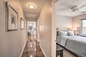A hallway with wooden flooring leading to a bedroom with a bed, a ceiling fan, and a nightstand with a lamp. - Family Home in Walkable Area Near Silicon Valley! (San Jose)