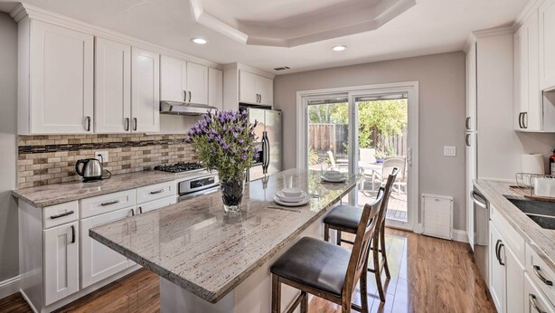 A modern kitchen with white cabinets, a granite countertop, and a central island with seating.