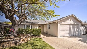 A residential house with a garage, a tree, and a well-maintained lawn.