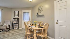 A dining area with a wooden table and chairs, a clock on the wall, and a bookshelf. - Centrally Located South Hill Apartment w/ Smart TV (Spokane)
