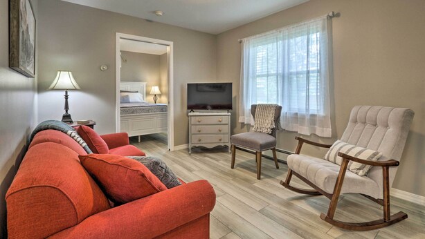 A living room with a sofa, a rocking chair, a television, and a window with curtains. - Centrally Located South Hill Apartment w/ Smart TV (Spokane)