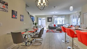 A modern kitchen with a central island, a dining area with red chairs, and a living room with a sofa and a large window. - 9 Mi to Disney: Davenport Resort Home w/ Pool (Davenport)