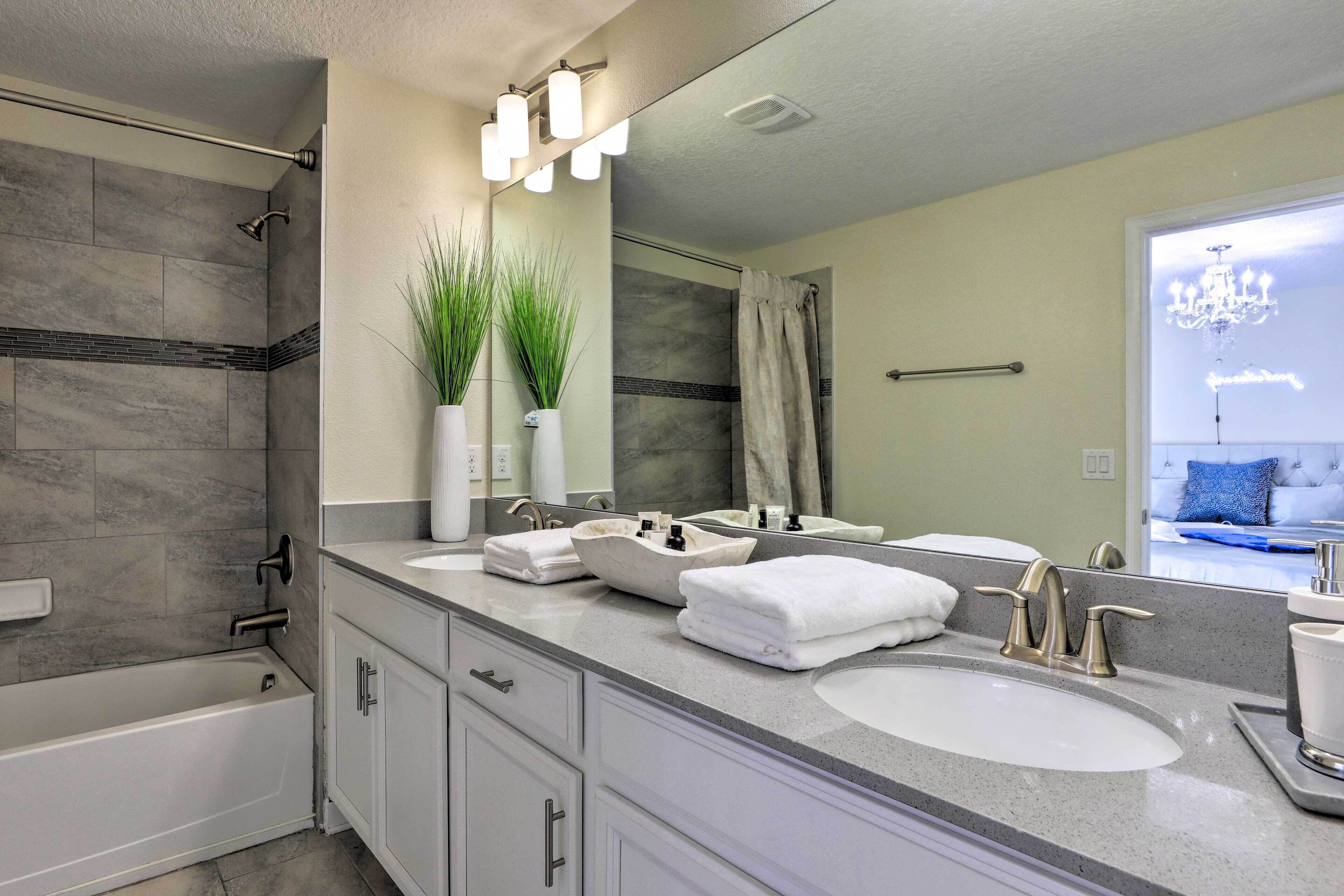 A modern bathroom with a bathtub, two sinks, and a large mirror.
