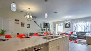 A modern kitchen with a central island, stainless steel appliances, and red chairs. - 9 Mi to Disney: Davenport Resort Home w/ Pool (Davenport)