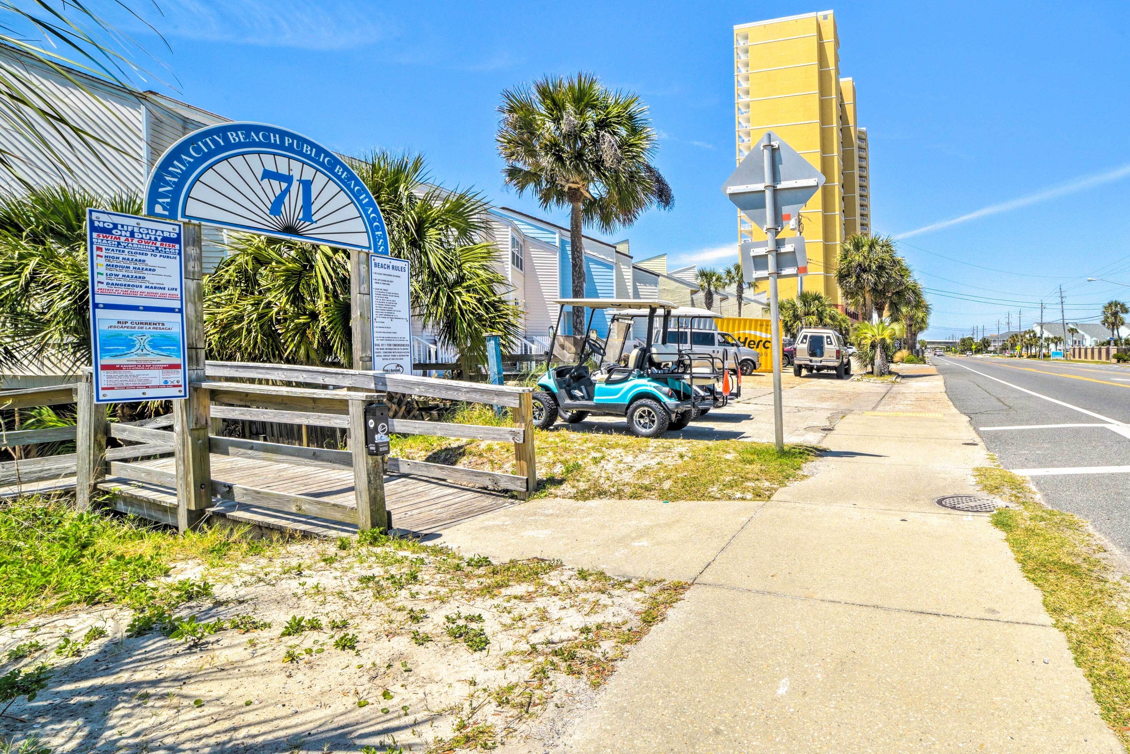 A beach entrance sign, a wooden boardwalk, and a parked golf cart.