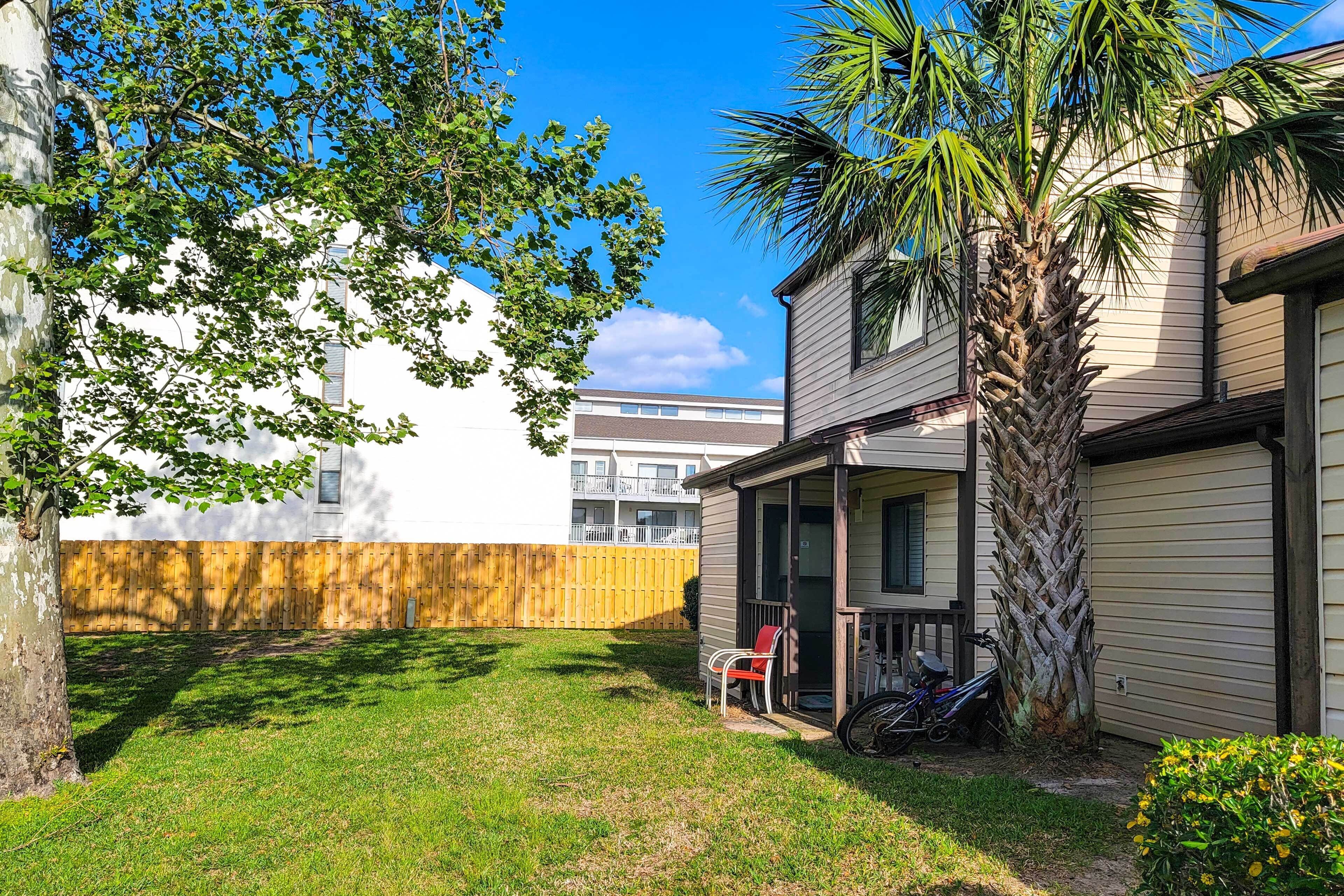 A residential property with a covered porch, a palm tree, and a wooden fence.