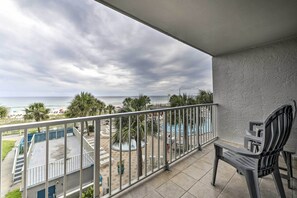 Un balcón con vistas al océano, una zona de piscina y una silla.