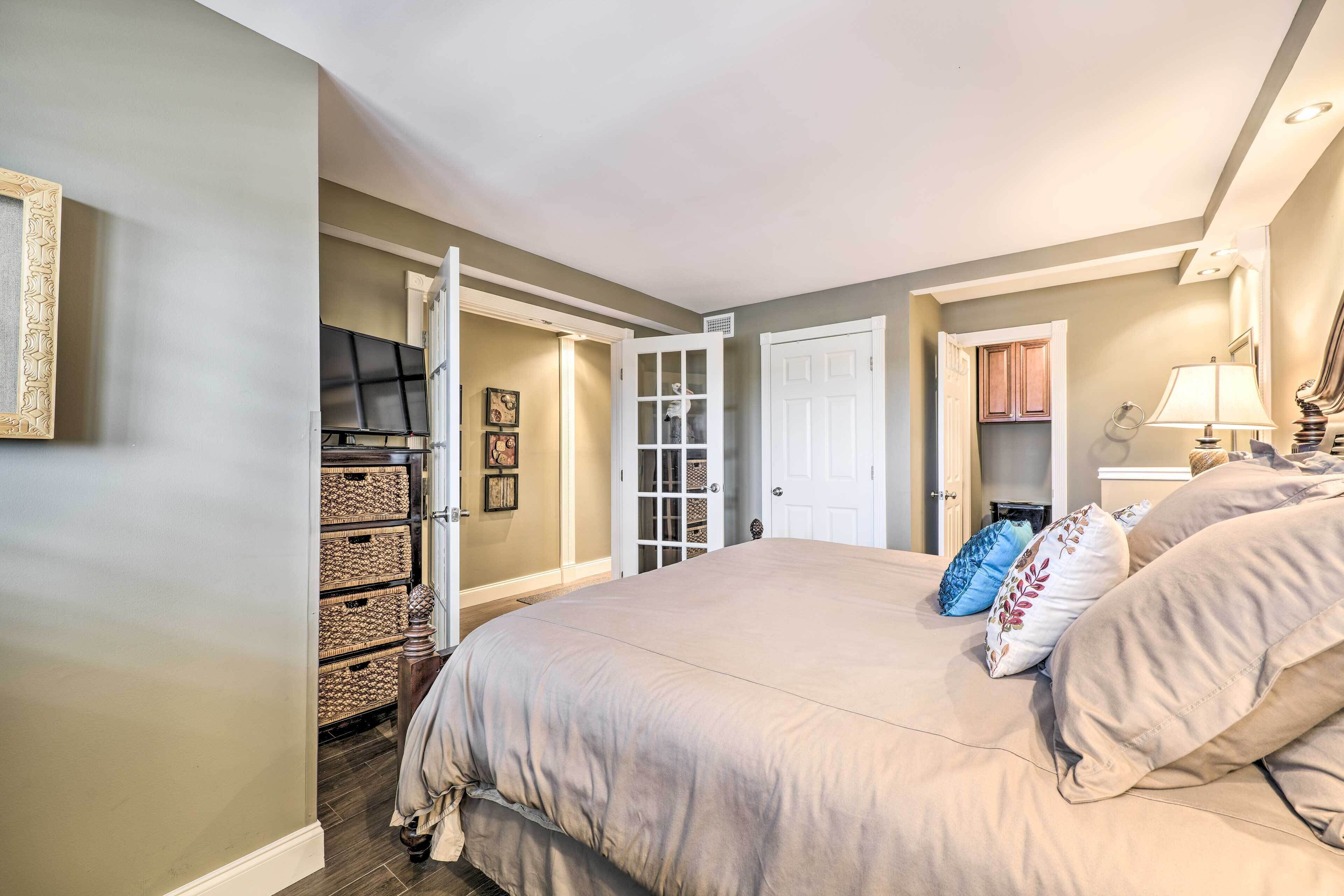 A bedroom with a large bed, a wardrobe, a door, and a television.