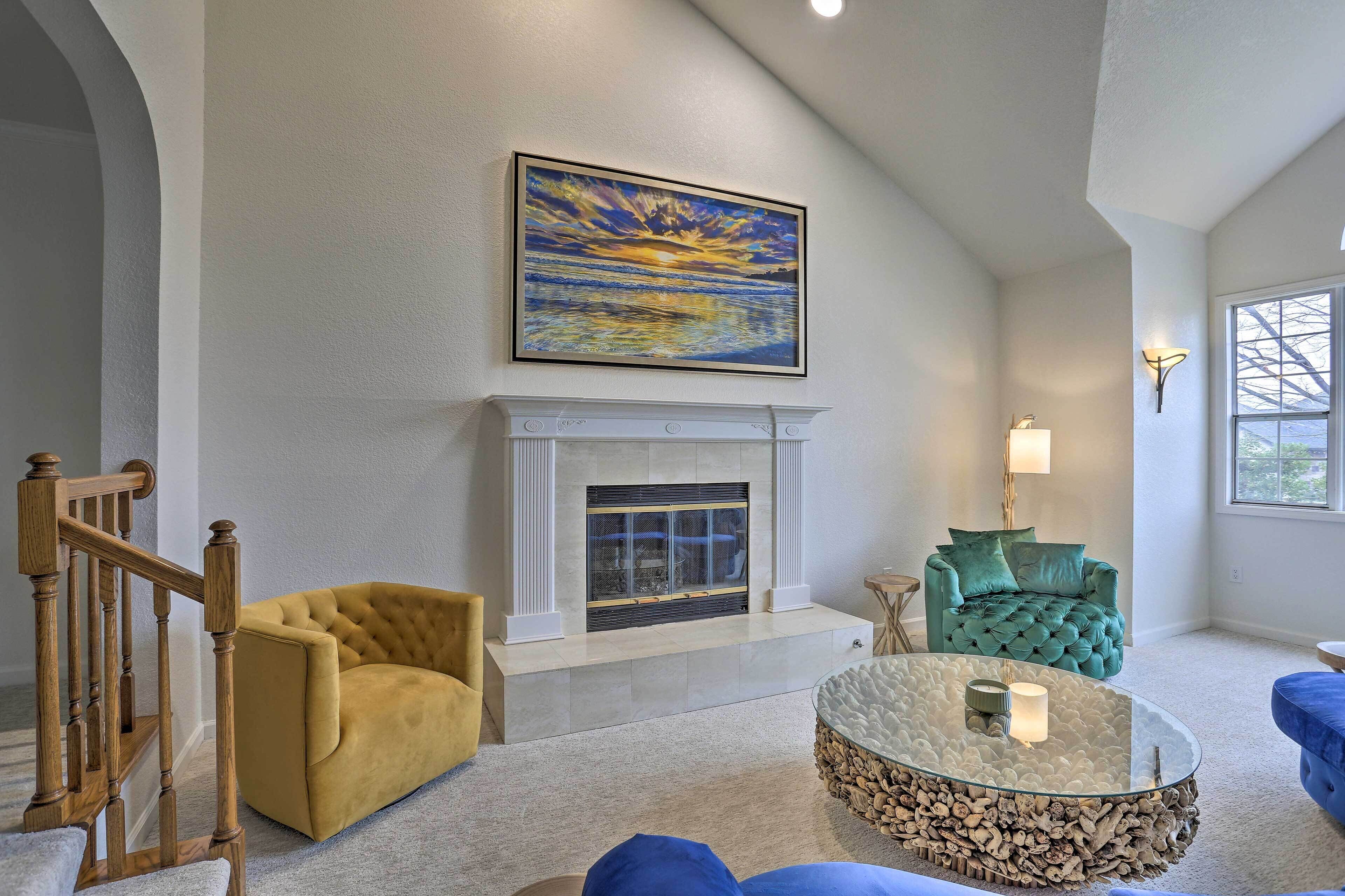 A living room with a fireplace, a staircase, and a large painting on the wall.