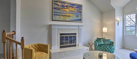 A living room with a fireplace, a staircase, and a large painting on the wall.