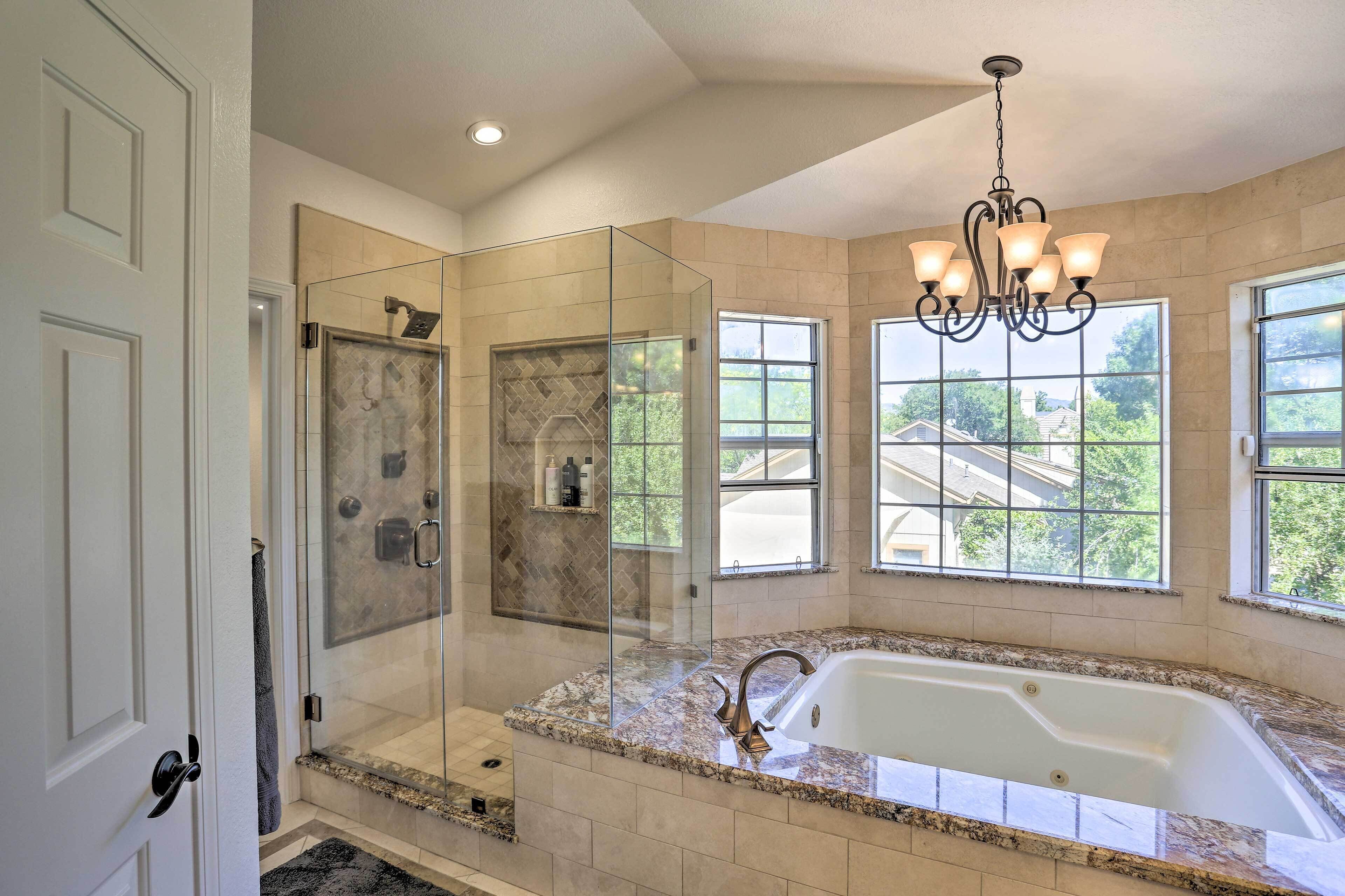 A modern bathroom with a glass-enclosed shower, a freestanding bathtub, and large windows offering a view of the outside.