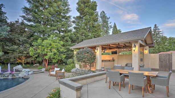 A covered outdoor patio with a pool, dining area, and stone steps leading to a wooden deck. - Redding Getaway w/ Hot Tub & Outdoor Kitchen! (Redding)