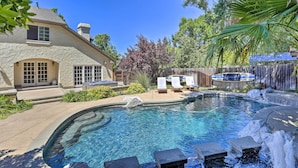 A backyard with a swimming pool, stone house, and outdoor seating area. - Redding Getaway w/ Hot Tub & Outdoor Kitchen! (Redding)