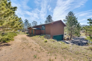 A building with a dirt path leading to it, surrounded by trees and a clear sky. - Estes Park Home w/ AC - 1/2 Mi to Lake & Downtown! (Estes Park)