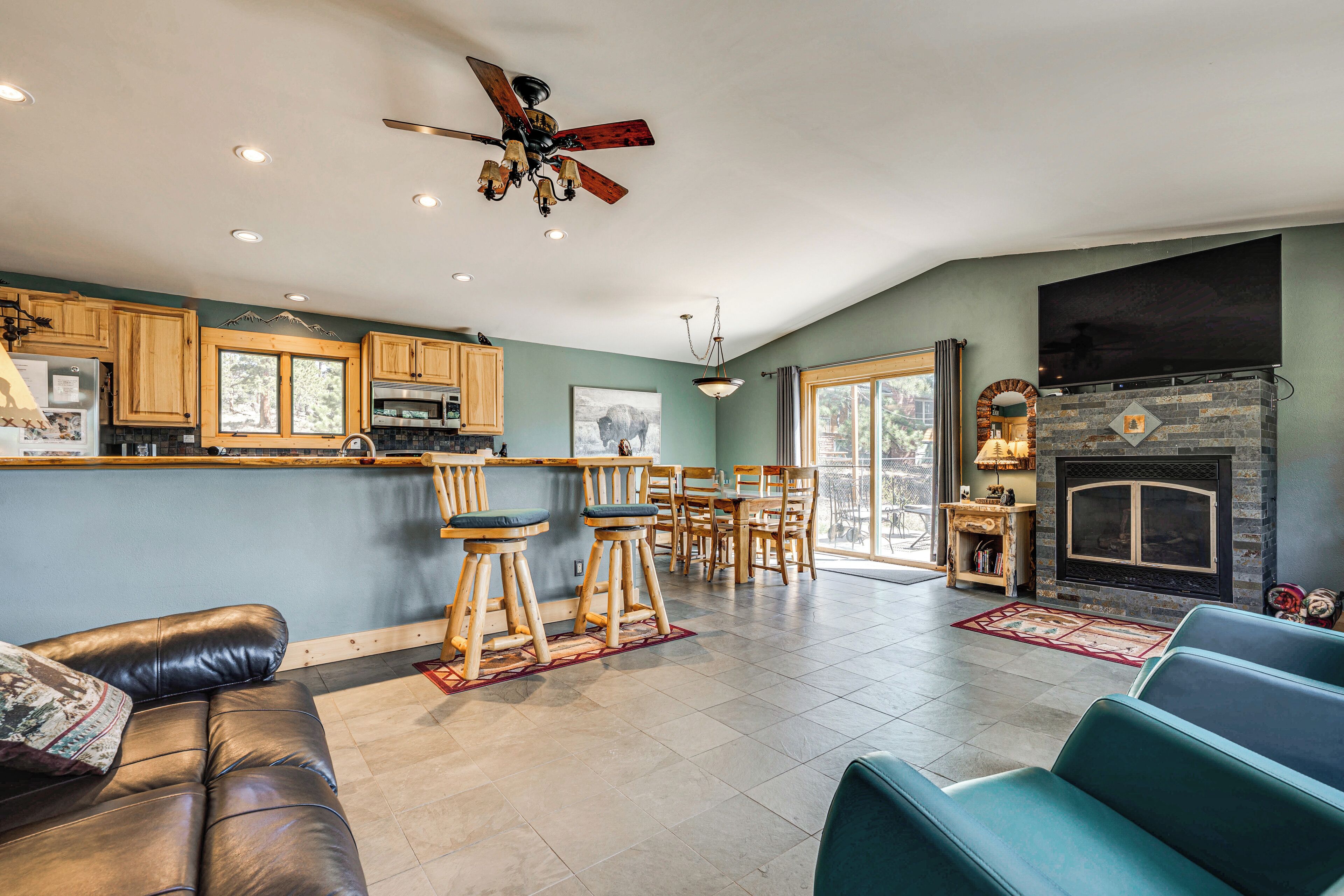 A modern kitchen with wooden cabinets, a bar area, a dining set, and a fireplace.