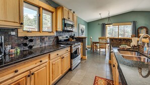 A kitchen with wooden cabinets, a stove, and a sink. - Estes Park Home w/ AC - 1/2 Mi to Lake & Downtown! (Estes Park)