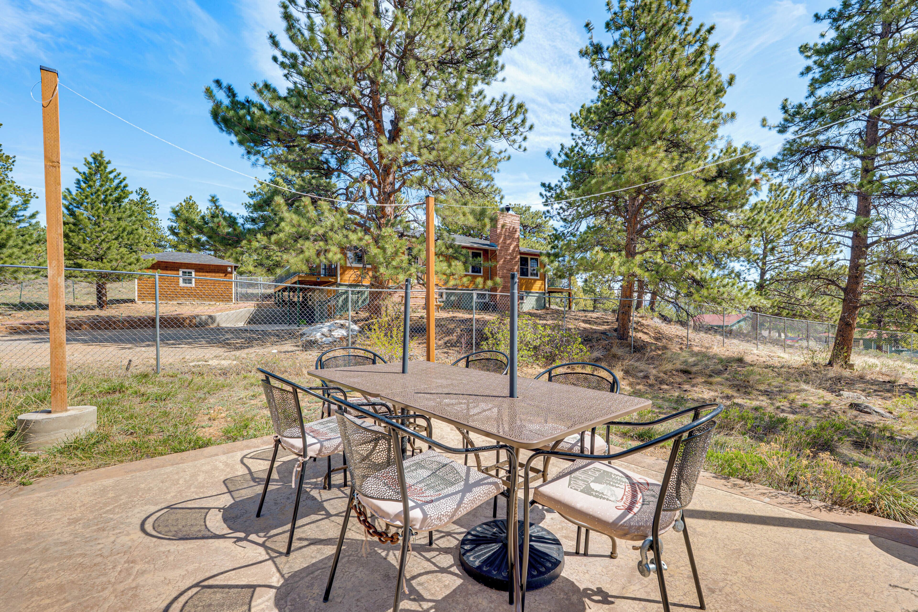 A patio with a table and chairs, surrounded by a fence and trees.