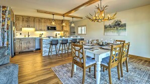 A spacious kitchen with wooden cabinets, a central island, and a dining area with a chandelier. - Mtn/lake Views & 3 Mi to Skiing: Dillon Condo (Dillon)