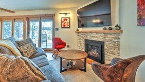 A modern living room with a fireplace, a large TV, and a red chair. - Mtn/lake Views & 3 Mi to Skiing: Dillon Condo (Dillon)
