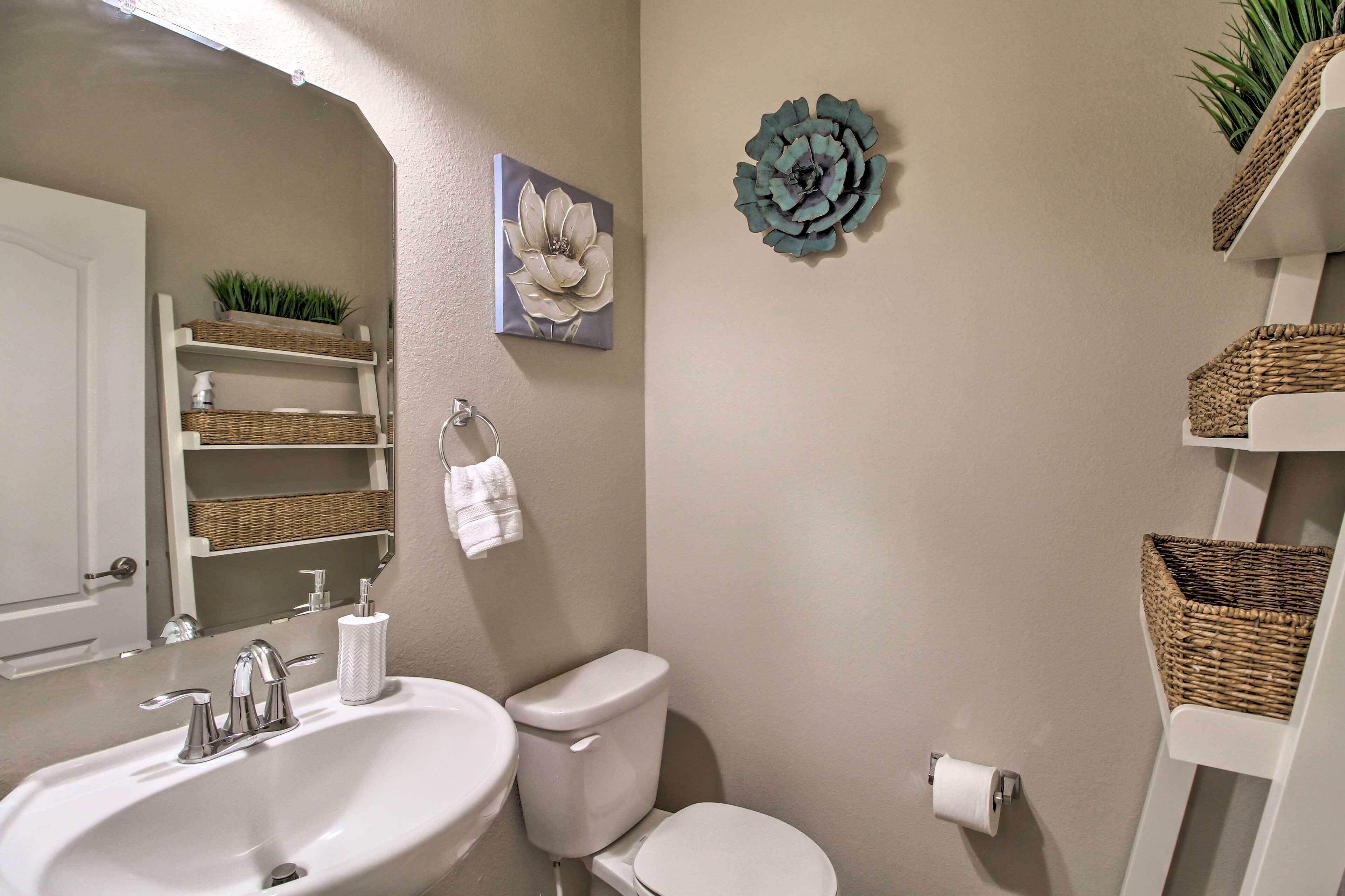 A bathroom with a sink, toilet, and wicker baskets on shelves.