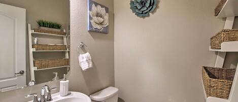 A bathroom with a sink, toilet, and wicker baskets on shelves.