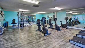 Ein Fitnessstudio mit Trainingsgeräten, Spiegeln und Holzboden.
