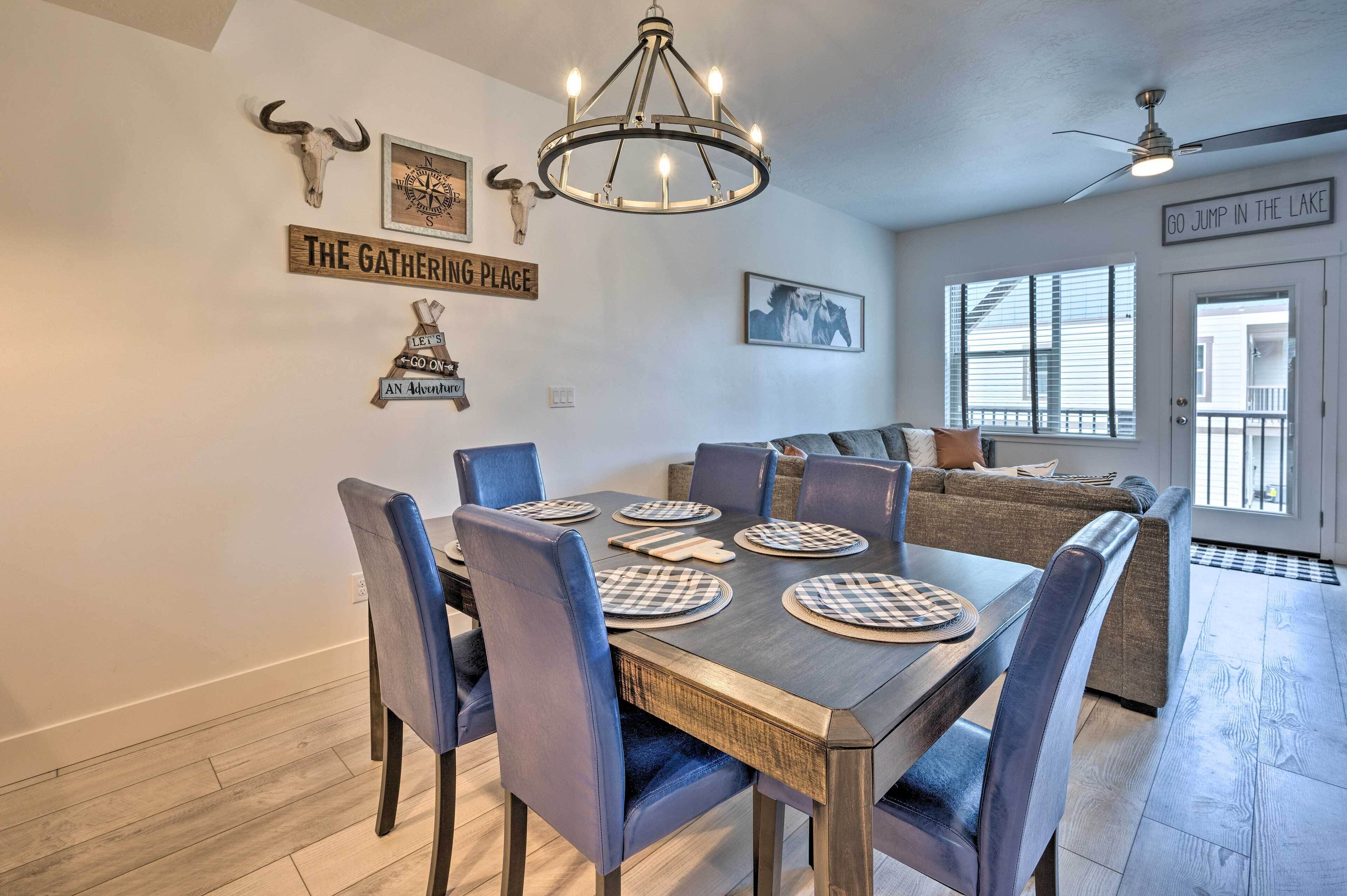 A dining area with a wooden table set for six, surrounded by blue chairs.