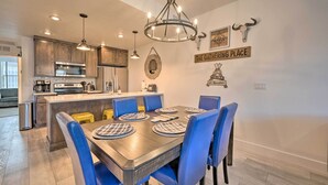 A modern kitchen with wooden cabinets, stainless steel appliances, and a central island with blue chairs. - Charming Mccall Townhome: Hike, Fish, & Ski! (McCall)