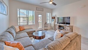 A living room with a sectional sofa, a round coffee table, a ceiling fan, and a television on a wooden cabinet. - Charming Mccall Townhome: Hike, Fish, & Ski! (McCall)
