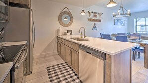 A modern kitchen with a central island, stainless steel appliances, and a dining area with a large table and chairs. - Charming Mccall Townhome: Hike, Fish, & Ski! (McCall)