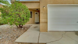 Un immeuble résidentiel avec un portail de garage, un petit arbre et une allée en béton.