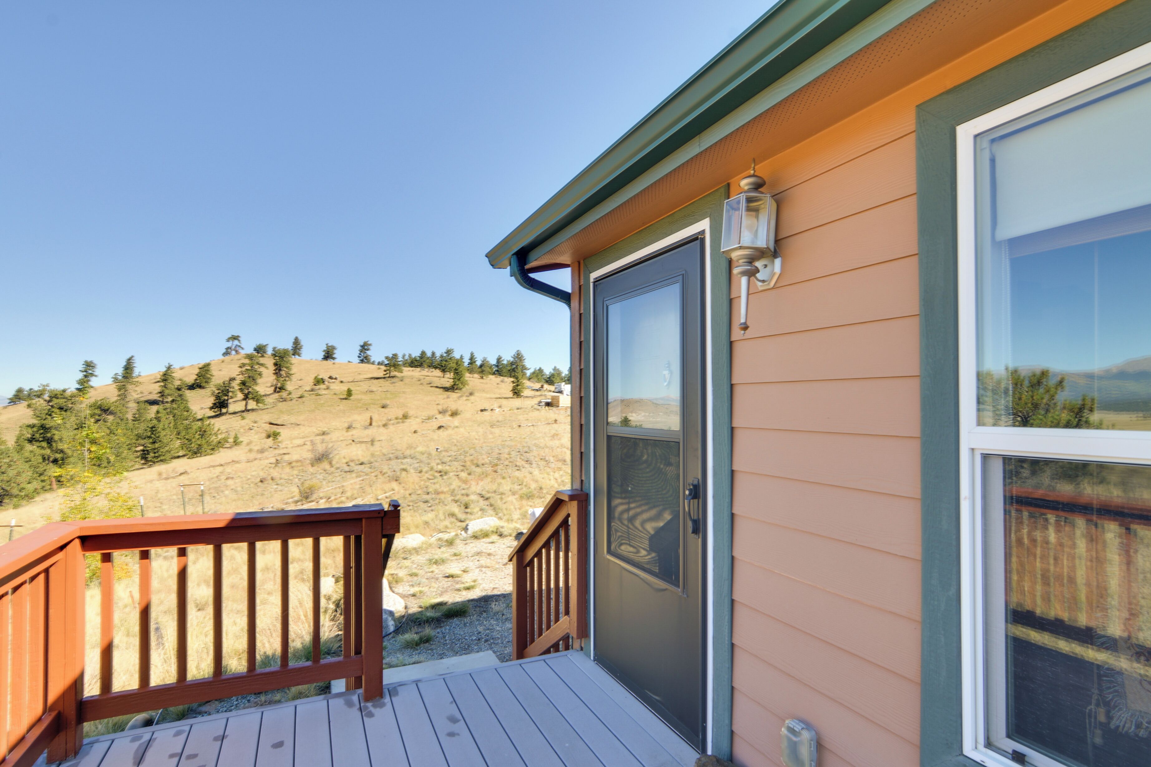 A wooden deck with a glass door leading to a room with a mountain view.