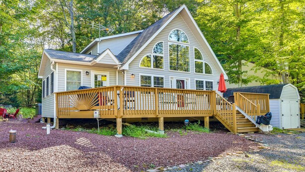 Une maison à deux étages avec une terrasse en bois et un porche couvert.