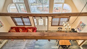 Un intérieur spacieux avec un canapé rouge, une table à manger en bois et de grandes fenêtres offrant une vue sur l’extérieur.