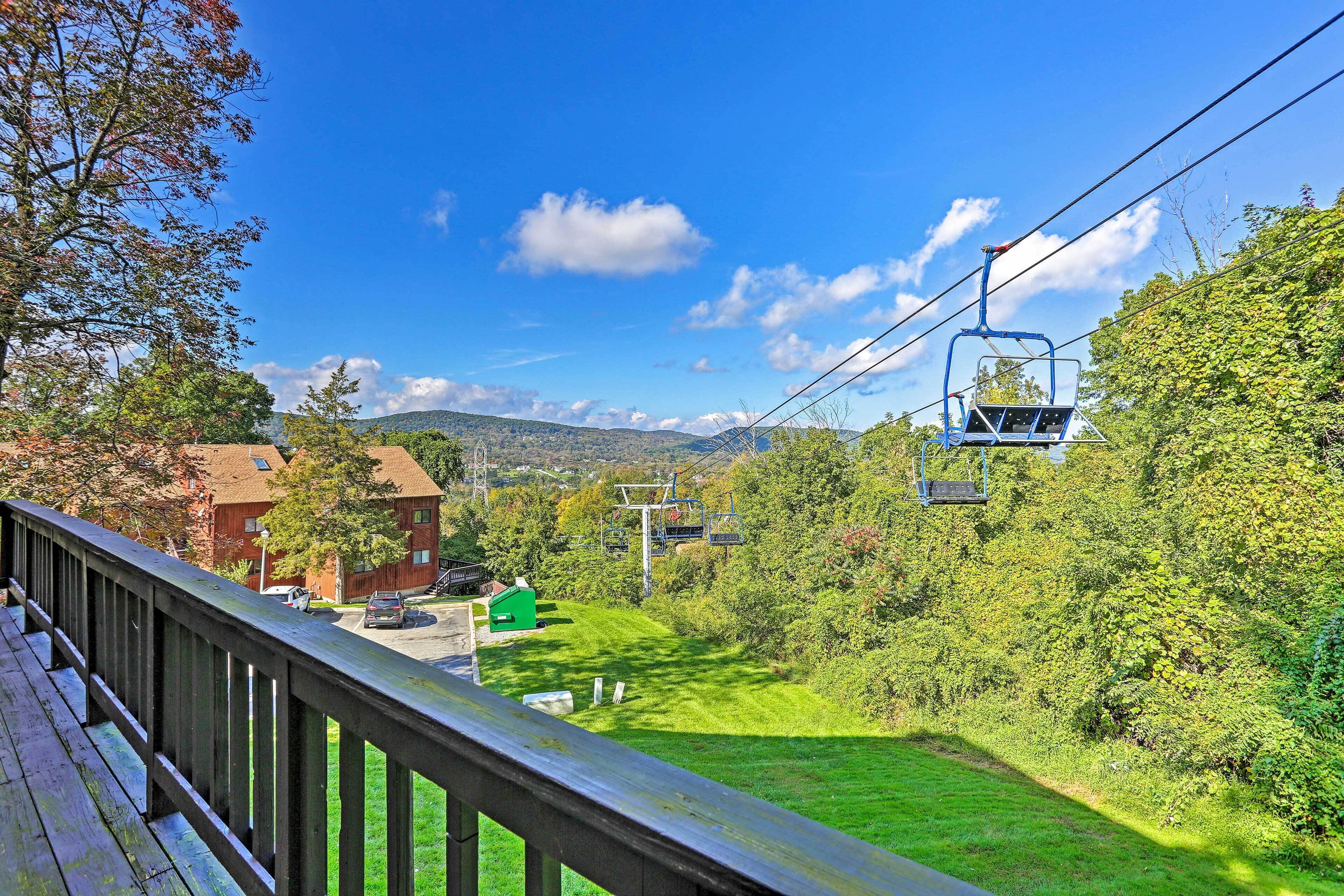 A view from a wooden deck overlooking a green landscape with a cable car system.