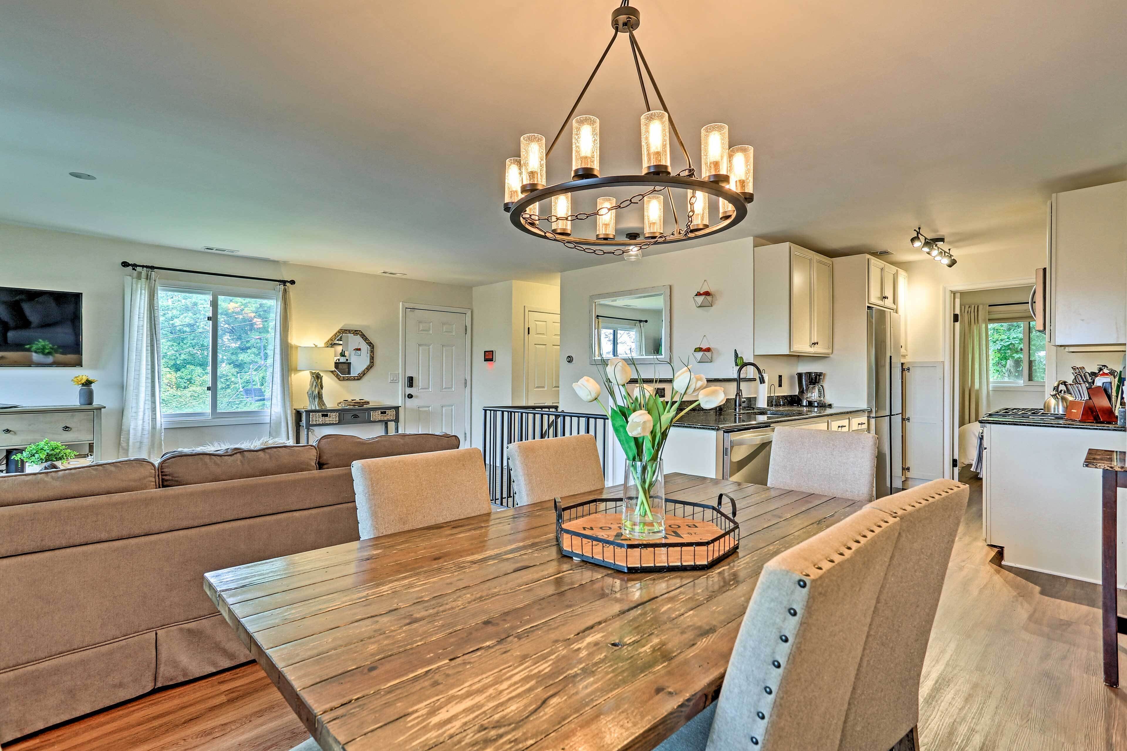 A spacious living room with a wooden dining table, beige sofas, and a chandelier.