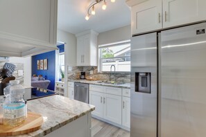 A modern kitchen with white cabinets, a stainless steel refrigerator, and a marble countertop. - Coastal Sarasota Condo: Minutes to Beach! (Sarasota)