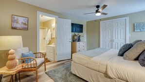 A bedroom with a bed, a chair, a desk, a dresser, and a door leading to a bathroom. - Kerrville Vacation Rental Across From River Trail! (Kerrville)