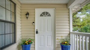 A front door with a white door and a small window above it, flanked by two blue flower pots on either side. - Kerrville Vacation Rental Across From River Trail! (Kerrville)