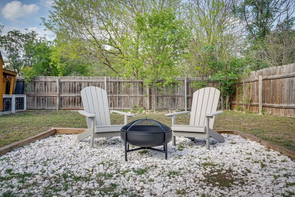 Un jardin avec deux fauteuils Adirondack, un barbecue noir et une terrasse en bois.